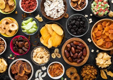 Çeşitli organik sağlıklı kurutulmuş tatlı böğürtlen ve meyveli aperatif siyah arka planda çeşitli kase tabakları.