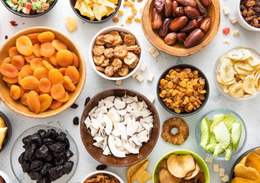 Çeşitli organik kurutulmuş tatlı meyve ve böğürtlen tabakları hafif mutfak arka planında..