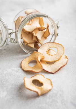 Işık panosunda kurumuş elma halkaları olan cam mutfak kavanozu..