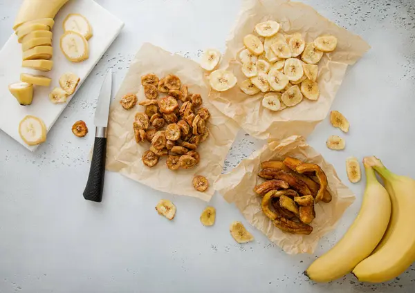 Various crunchy and chewy banana slices and chips snack with raw banana and knife.