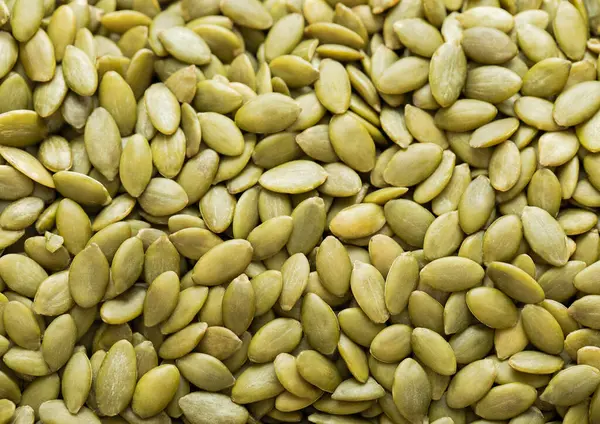 stock image Healthy peeled green pumpkin seeds top view macro background.