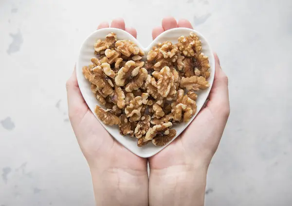 Female Hands Holding Heart Shaped Plate Healthy Peeled Walnut Nuts Стоковое Фото