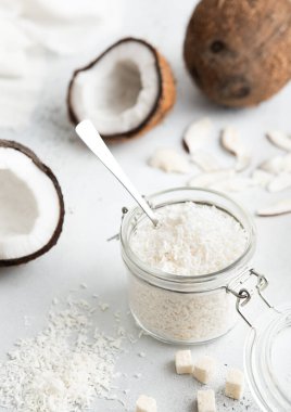 Cam kavanozda öğütülmüş hindistancevizi taneleri ve olgun hindistan cevizleri. Makro.