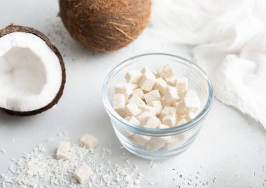 Hafif arka planda cam kasede öğütülmüş gevrekten yapılmış kurutulmuş hindistan cevizi ısırıkları..