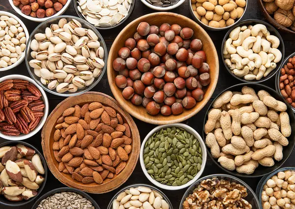 Smíšené Zdravé Ořechy Semena Různých Miskách Stole Tmavé Kuchyně Arašídy — Stock fotografie