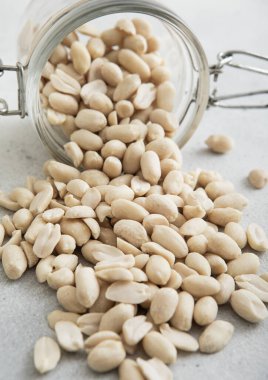 Beyaz mutfak masasında cam kavanozda çiğ, soyulmuş fıstık..