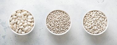 Mutfak masasında çeşitli boyutlarda kuru fasulye tabakları var..