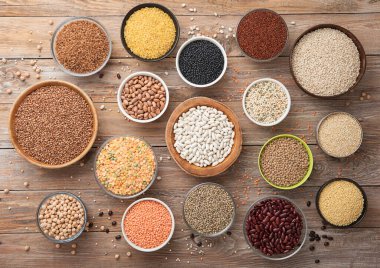 Bulgur, fasulye, kinoa, bezelye, kuskus ve ahşap mutfak arka planında çeşitli çanaklarda nohut ve karabuğday tohumları bulunan kenevir..