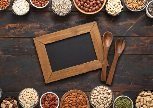 Арахис, фундук, грецкий орех, миндаль, фисташка, подсолнух, тыква, чиа, пекан и кешью смешали здоровые орехи и семена с доской для меню и кухонной утварью.