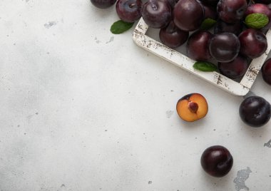 Açık mutfak arka planında ham olgun mor eriklerden oluşan ahşap kutu..