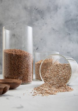 Kahverengi ve yeşil çiğ organik karabuğday tohumları cam kavanozda açık mutfak masasında.