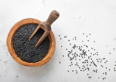 Çiğ siyah mercimek tohumları ahşap kasede ve ışık masasında kepçeyle..