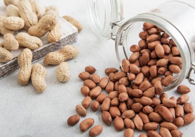 Çiğ soyulmuş ve bütün fıstık beyaz mutfak masasında cam kavanozda..