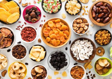 Çeşitli organik kurutulmuş tatlı meyve ve böğürtlen tabakları hafif mutfak arka planında..