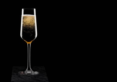 Sarı şampanya kabarcıklar siyah arka plan üzerine siyah mermer gemide ile zarif bardak.