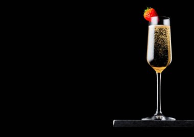 Zarif bardak çilek üst siyah arka plan üzerine siyah mermer gemide ile sarı şampanya. 
