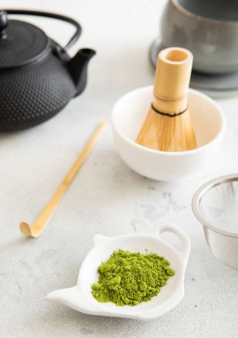 Bambu kaşıklı kibrit yeşil çay tozu ve seramik kasede çırpma, beyaz üzerine demir çaydanlık..
