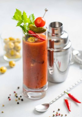 Viski bardağında Bloody Mary kokteyli, karıştırıcı ve hafif bardakta zeytin ve kırmızı biberli kaşık. Üst görünüm