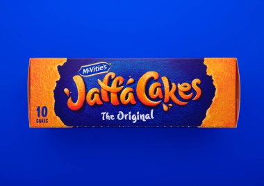 LONDON, İngiltere - 31 Ocak 2025: Bir kutu Jaffa Kek bisküvisi turuncu marmelatla doldurulmuş ve üstü mavi arka planda sütlü çikolatayla kaplanmış.