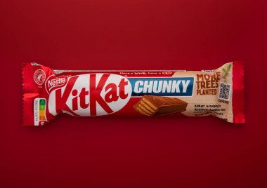 LONDON, İngiltere - 27 HAZİRAN 2025: Kırmızı arka planda KitKat çikolatalı gofret çıtır bisküvi.
