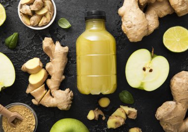 Bir şişe enerji içeceği. Zencefilli ve yeşil elmalı. Siyah arka planda limonlu..