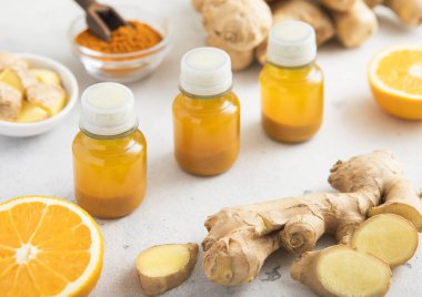 Zencefil kökü ve açık arkaplanda olgun portakallarla bağışıklık aşısı içeceği..