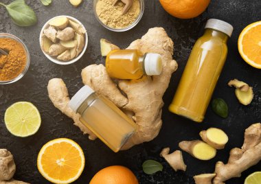 Zencefil ve turuncu enerji şişeleri zencefil kökü ve siyah zemin üzerinde zerdeçal tozu ile içilir..