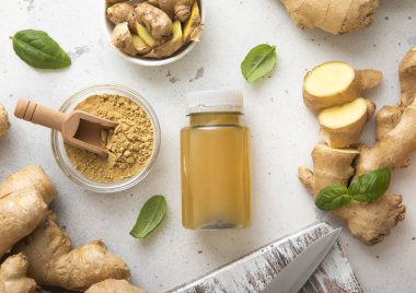 Bir şişe zencefilli enerji içeceği, zencefil kökü ve hafif arka planda topraklanmış toz..