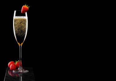 Zarif bir bardak sarı şampanya üzerinde çilek ve siyah mermer tahtada taze böğürtlen..