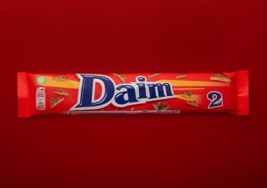 LONDON, İngiltere - Şubat 05, 2025: Kırmızı üzerine sütlü çikolata kaplı duble Daim karamel badem barı.