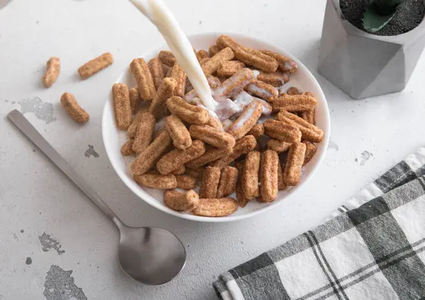 Tatlı churros kahvaltı gevreği tabakta ve üzerine kaşıkla süt dök..