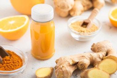 Bağışıklık turuncusu ve zerdeçal enerji içeceği. Hafif arkaplanda zencefil kökü ve zerdeçal tozu var..
