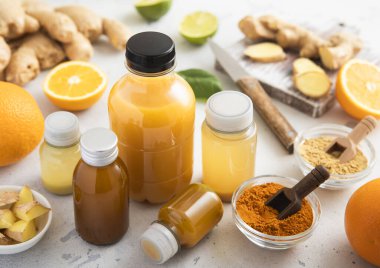 Çeşitli bağışıklık güçlendirici şişeler açık arkaplanda zencefil, turuncu ve zerdeçal içeren shot içecekler.