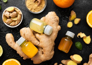 Zencefil ve turuncu enerji şişeleri zencefil kökü ve siyah zemin üzerinde zerdeçal tozu ile içilir..