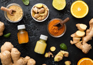 Bağışıklık sistemli zencefilli enerji içeceği taze zencefil kökleri ve siyah arka planda portakal meyveleri..