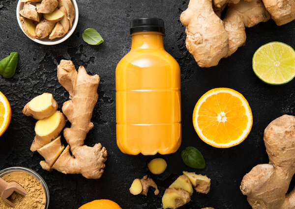 Иммунный имбирь и апельсиновая энергия выстрел напиток с корнем имбиря и куркумы порошок на черном фоне кухни.