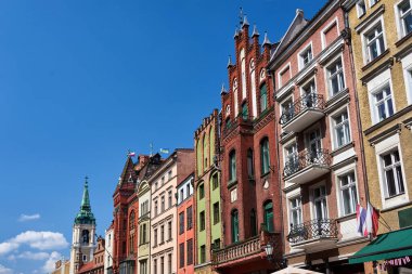 Bir kilisenin çan kulesi ve Polonya 'nın Torun kentindeki tarihi apartman binalarının cepheleri.