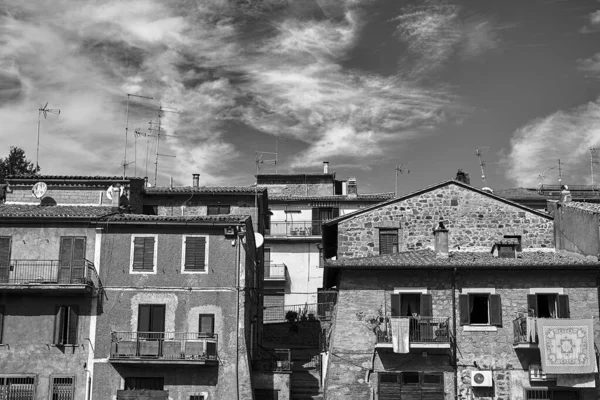 Roofs with antennas and walls with windows and balconies in a small town in Tuscany, Italy, monochrome