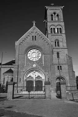 The facade of the historic neo-gothic catholic church with a bell tower in the city of Poznan, monochrome