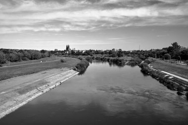 Historic, Gothic buildings and an industrial chimney on the Warta River in the city of Poznan, monochrome