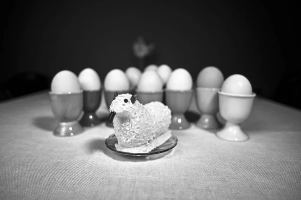 イースターの朝食のために用意されたテーブルの上でゆで卵のためのバターとカラフルな容器とイースター子羊 モノクロ — ストック写真