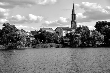 Polonya 'da bir göl kenarında gotik çan kulesiyle küçük bir kasaba olan Lubniewice manzarası.