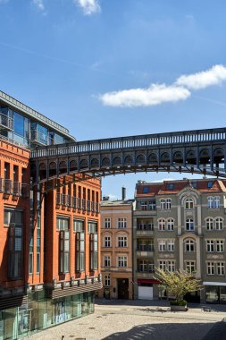 Poznan, Polonya 'daki eski bir bira fabrikasında metal köprü ve kırmızı tuğla bina.