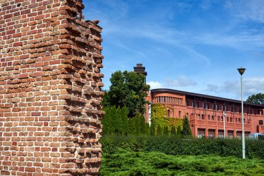 Polonya 'nın Poznan şehrinde bir ortaçağ savunma duvarı ve modern bir tuğla bina.