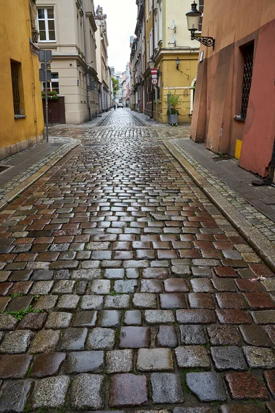 Polonya 'nın Poznan şehrinde kaldırım taşı caddesi ve tarihi apartman evleri yağmurdan sonra