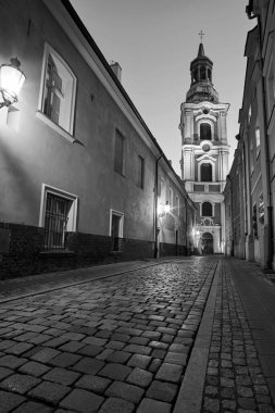 Geceleyin Poznan, Polonya 'da tarihi bir manastırın barok çan kulesi olan Cobblestone Caddesi.