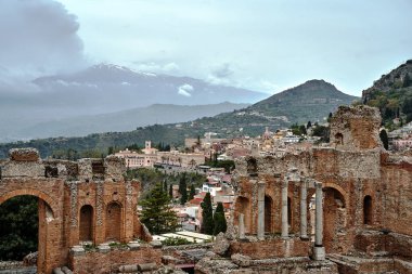 İtalya 'nın Sicilya adasındaki Taormina şehrindeki Etna volkanına bakan antik Yunan tiyatrosunun harabeleri ve taş sütunları.
