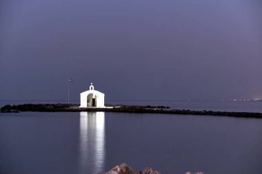 Yunanistan 'ın Girit adasındaki Georgioupoli kasabasındaki taştan bir mezarlıkta gece aydınlanan beyaz bir Ortodoks şapeli