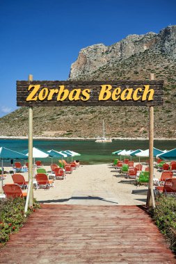 Deckchairs and umbrellas on the sandy beach of Zorbas in the town of Stavros on the island of Crete, Greece clipart