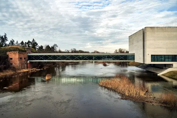 stock image modern concrete building, pedestrian bridge and walls of a historic Prussian fort on the Warta River in Poznan, Poland